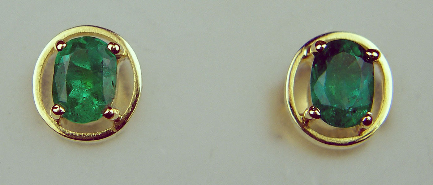 Oval Colombian emerald rubover earstuds in 14ct yellow gold